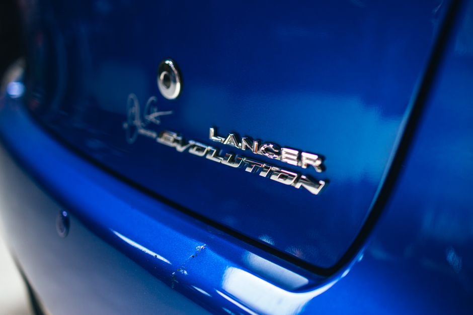 Detailed shot of a Mitsubishi Lancer Evolution badge on a vibrant blue car.